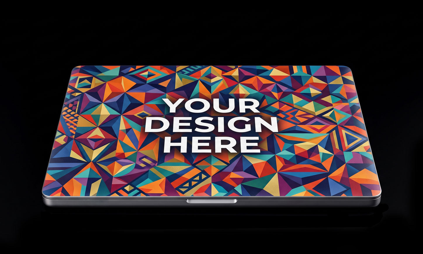 Closed MacBook with a colorful custom geometric skin on a black studio background